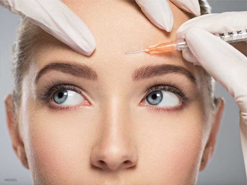 Woman getting filler injectables in her forehead.