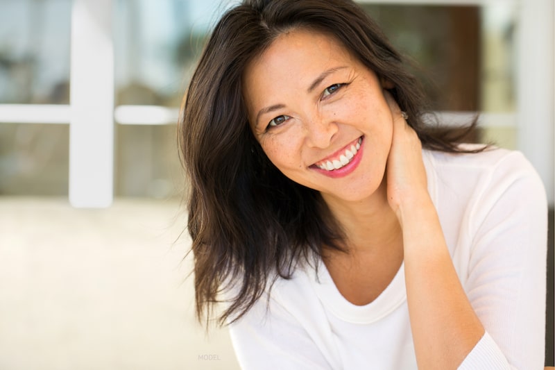 Beautiful, middle-aged Asian women smiling at camera on patio.