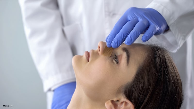 Doctor touching patient with nose bandage's nose