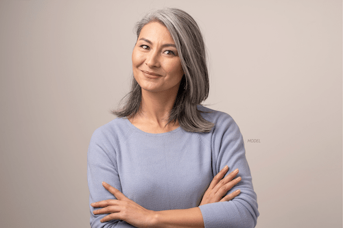 Middle-aged woman standing with her arms crossed.