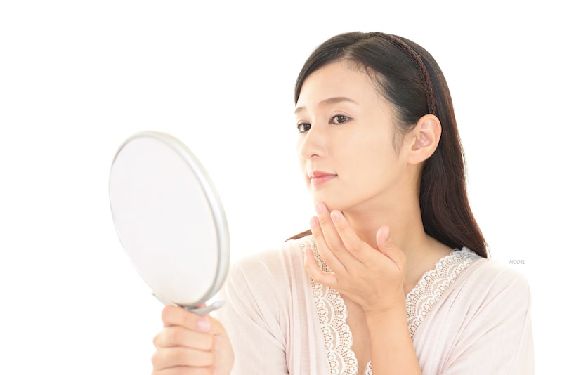 Beautiful Asian woman with clear skin looking in a mirror