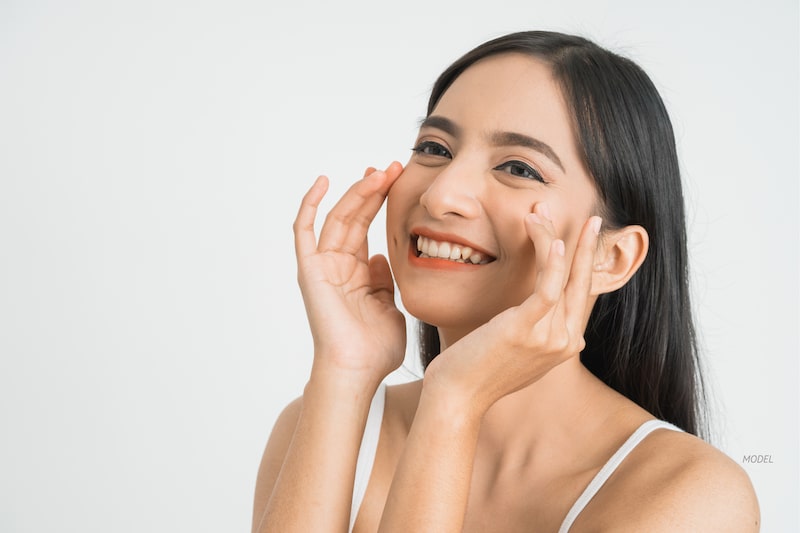 Beautiful Asian woman, smiling with her hands to her face