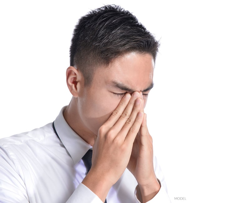 Attractive man holding his nose because of nasal pressure and pain